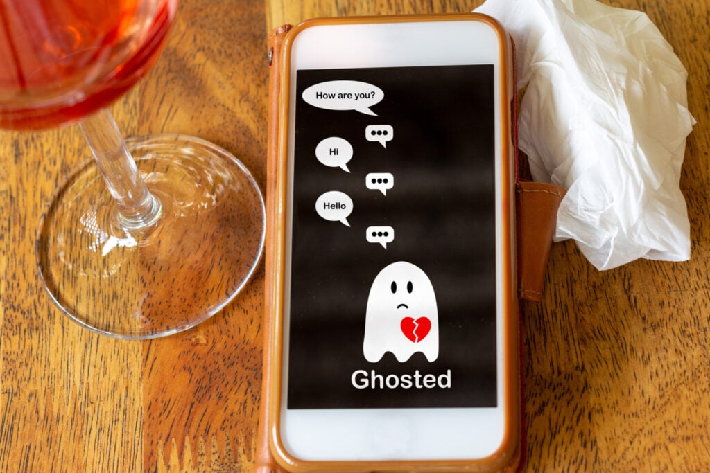 关系中的消失:你需要知道的一切 1 Ghosted on mobile phone on table with glass of wine and tissue, Ghosting to cut all communication without explanation, ending a relationship. Social media dating.