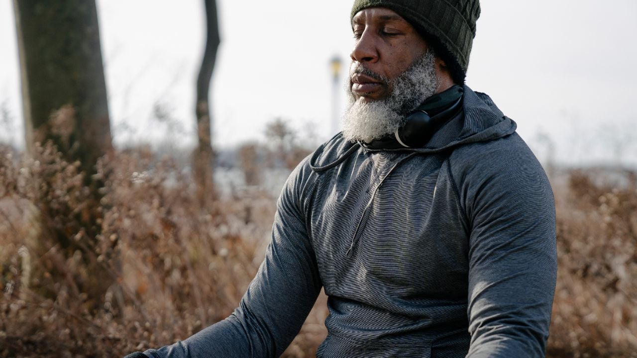 正念贯穿生命周期 一位老人在寒冷的日子里在大自然中完成正念冥想的照片